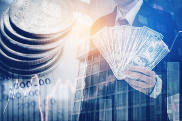 Wall Mural - Businessman Holding money US dollar bills on digital stock market financial exchange and Trading graph Double exposure city on the background