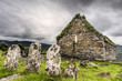 The three graves of an old Irish cemetery face the ruins of a stone church