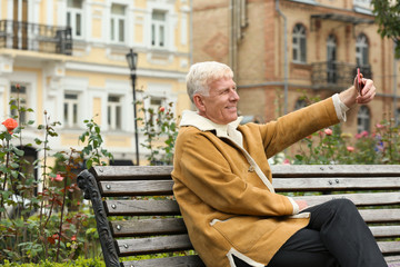 Handsome mature man taking selfie outdoors