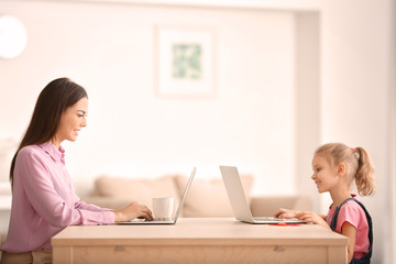 Wall Mural - Young woman and her daughter with laptops at home