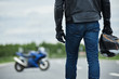 Summer lifestyle picture of European guy wearing protective helmet and leather jacket preapring for ride on his powerful sport bike, stay in front of motorbike. People, extreme and transportation