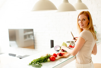 Pretty young woman preparing healthy meal in the kitchen