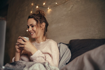 Wall Mural - Cheerful woman drinking coffee in bedroom