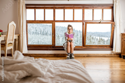 Young Woman In Sweater Sitting Near The Big Window At The