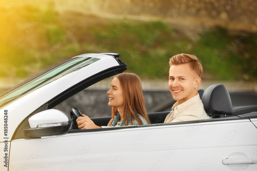 Happy young couple in car on road trip