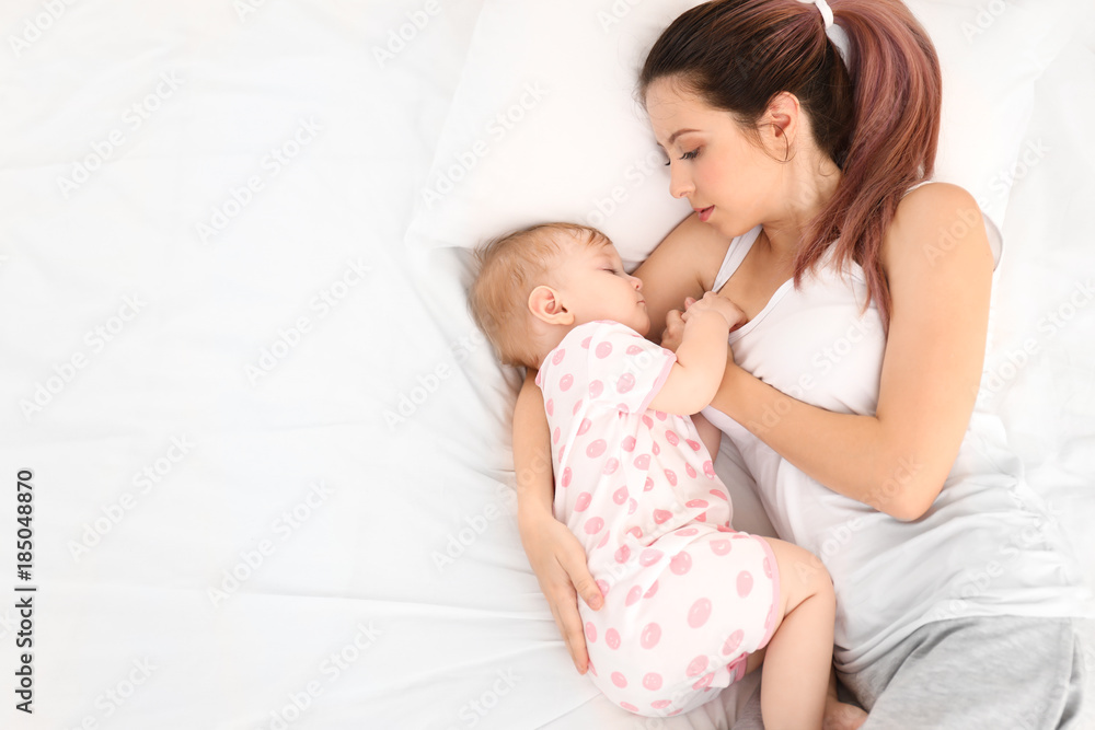 Young mother with her cute baby on bed