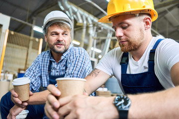 Wall Mural - Portrait of two workers wearing hardhats taking break from work drinking coffee and resting sitting on construction site
