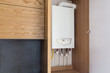 Opened kitchen cabinet and a gas boiler, a smart solution to hide the boiler inside furniture. Kitchen in a modern loft style with wooden details. 