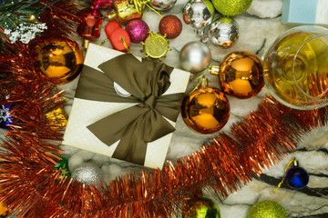 red Christmas present stands on the snow against a background of a Christmas balls and shiny tinsel