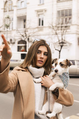 Wall Mural - beautiful brunette in elegant clothes with small dog walking on the street