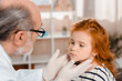 © LIGHTFIELD STUDIOS - senior pediatrician in medical gloves examining little patients throat in clinic
