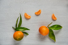 Three Tangerine Orange Slices On The Gray Wooden Board With Free Copy Space. Two Fresh Raw Mandarins Orange With Green Leaves And Peeled Yellow Tangerine. Top View