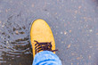 Wet boot in jeans standing in the muddy puddle