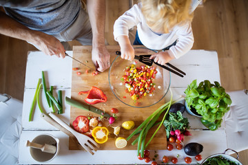 Wall Mural - Young father with a toddler boy cooking.