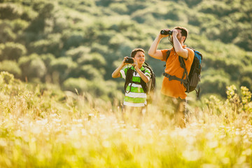 Father and son are hiking in nature in summer. Boy is photographing. 