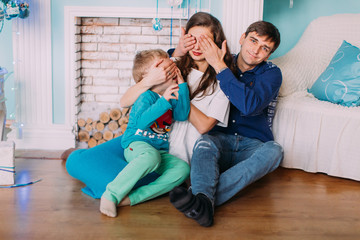 New Year's picture of happy family on background of Christmas decorations. Young parents with their son having fun and smiling on background of Christmas decorations