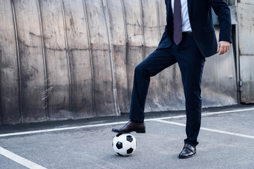 Wall Mural - partial view of businessman in suit playing soccer on street