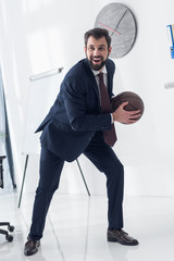 Wall Mural - young businessman in suit playing basketball in office