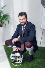 Wall Mural - smiling businessman with rugby helmet in office