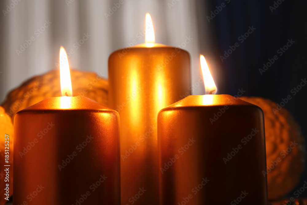 Metallic pillar candles burning on blurred background, closeup