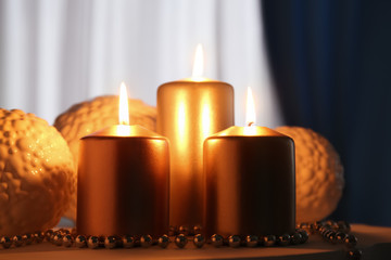 Wall Mural - Metallic pillar candles burning on table, closeup