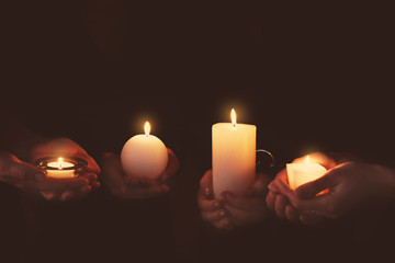 Wall Mural - Hands with burning candles on dark background