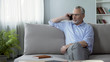 Caring retired father sitting on sofa and calling his children, communication
