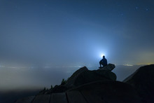 Silhouette Of Man Sitting On Mountain Peak Against Sky