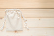 Canvas bag with drawstring, mock up of small eco sack made from natural cotton fabric cloth flat lay on white wood background from top view 