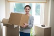 © WavebreakMediaMicro - Woman carrying cardboard boxes in living room