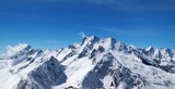 Fototapeta Góry - Panoramic view of snow covered mountain peaks and beautiful blue sky