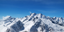 Panoramic View Of Snow Covered Mountain Peaks And Beautiful Blue Sky