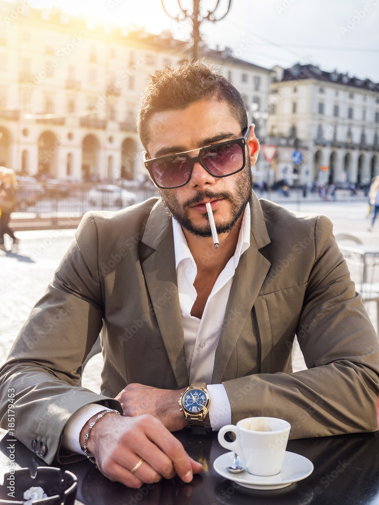 espresso and cigarette Photo Stock Handsome young man drinking espresso coffee and smoking  cigarette, wearing elegant coat posing at table outside on urban  background