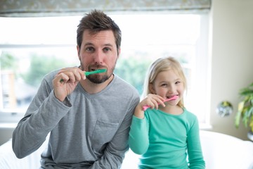 Father and daughter brushing teeth in the bathroom