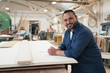 © Jetta Productions/Stocksy - Side portrait of smiling hispanic cabinet shop worker