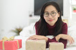 © pixindy - Asian woman girl in warm red sweater lying in bed at home with gift box.