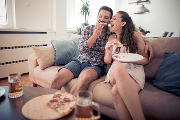 Poster - Happy young couple eating pizza in the living room.