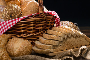 Close up of Baked Bread with basket; Various fresh bread such as sesame bun, baguette, baked rolls, croissant, round bun and whole grain sliced bread