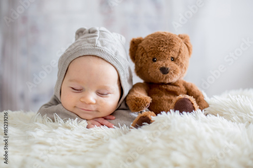 Cuadros en Lienzo Sweet baby boy in bear overall, sleeping in bed with teddy bear