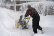 © jollier_ - A man cleans snow from sidewalks with snowblower.