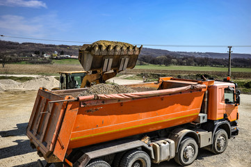 Gravel pit excavation site on a sunny day with industrial machines.