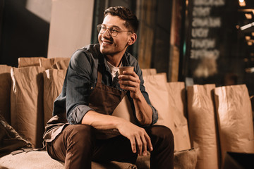 Wall Mural - smiling coffee roster with cup of coffee having break during work