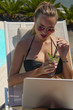 Kobieta pracująca na laptopie. Dziewczyna na wakacjach. Praca w podróży. Praca zdalna.  Na basenie.