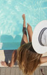 Kobiece nogi na basenie. Zdrowa skóra. Ochrona przed promieniowaniem UV.  Kobieta w kapeluszu na basenie. 