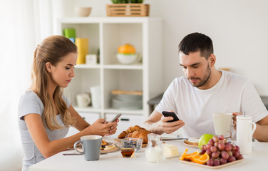 Wall Mural - couple with smartphones having breakfast at home