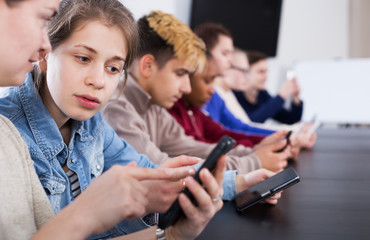 Wall Mural - Male and female students playing with smartphones