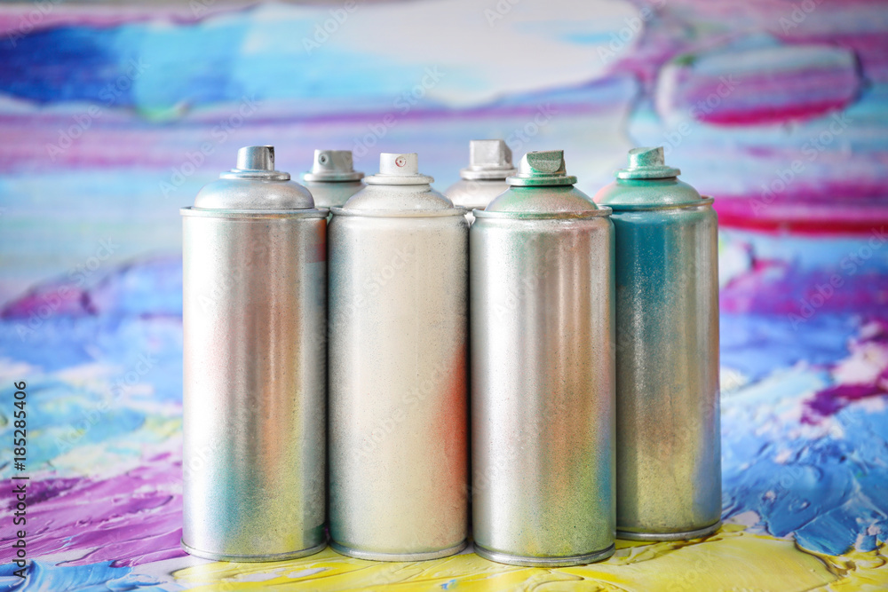 Aluminum aerosol cans with paints against blurred background