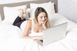 © Louis-Paul Photo - Young woman using laptop on bed