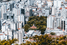View From High Point Of Modern Urban Cityscape On Very Bright Summer Day: Multiple Multistorey Residential And Office Buildings, Park With Church In Center, Streets With People; Juiz De Fora, Brazil
