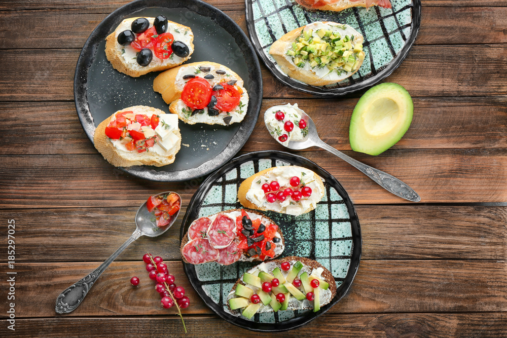 Plates with tasty bruschettas on wooden background